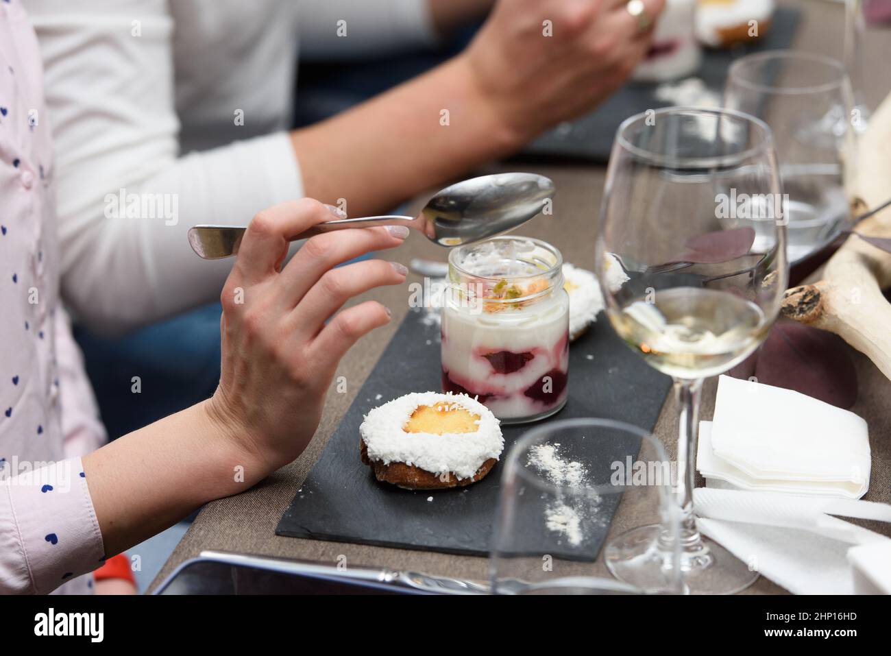 Une femme mange un dessert dans une tasse de verre, avec du Jello, du yaourt et de la garniture servis dans un restaurant. Mini desserts Banque D'Images