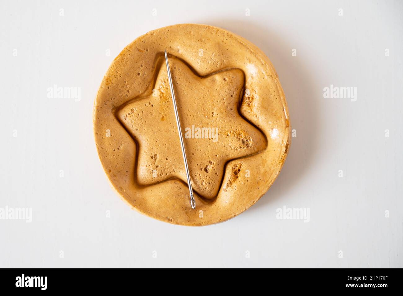 Biscuits de sucre brun caramel avec une aiguille en métal en forme d'étoile sur fond blanc. Banque D'Images