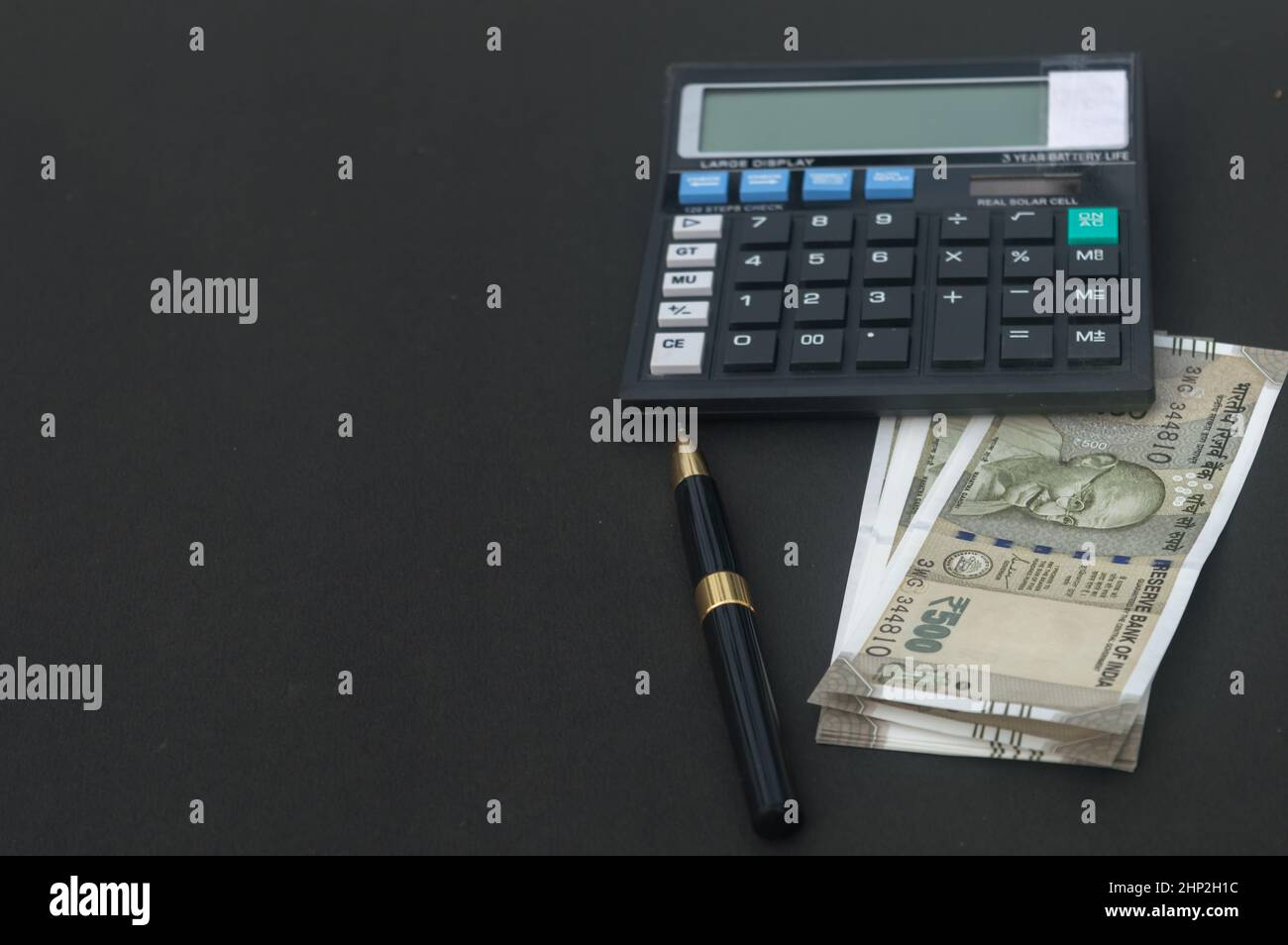 Indian Rupee placé près de la calculatrice et un stylo sur la table.Isolé sur fond noir. Banque D'Images