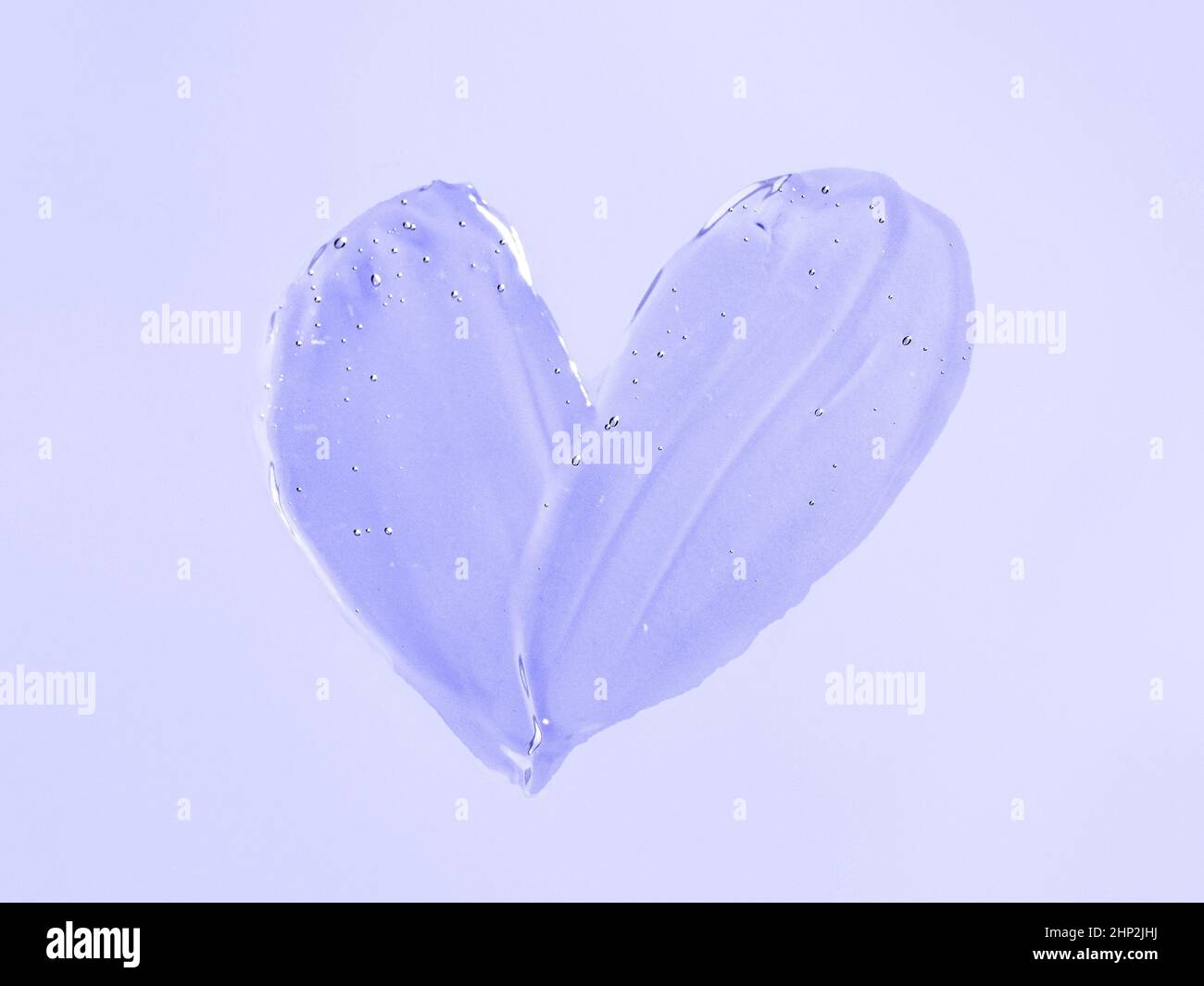 Gel liquide texture à effet de tache cosmétique en forme de coeur sur fond violet ou violet. Esthétique magnifique texture frottis transparent gel ou masque pour la peau Banque D'Images