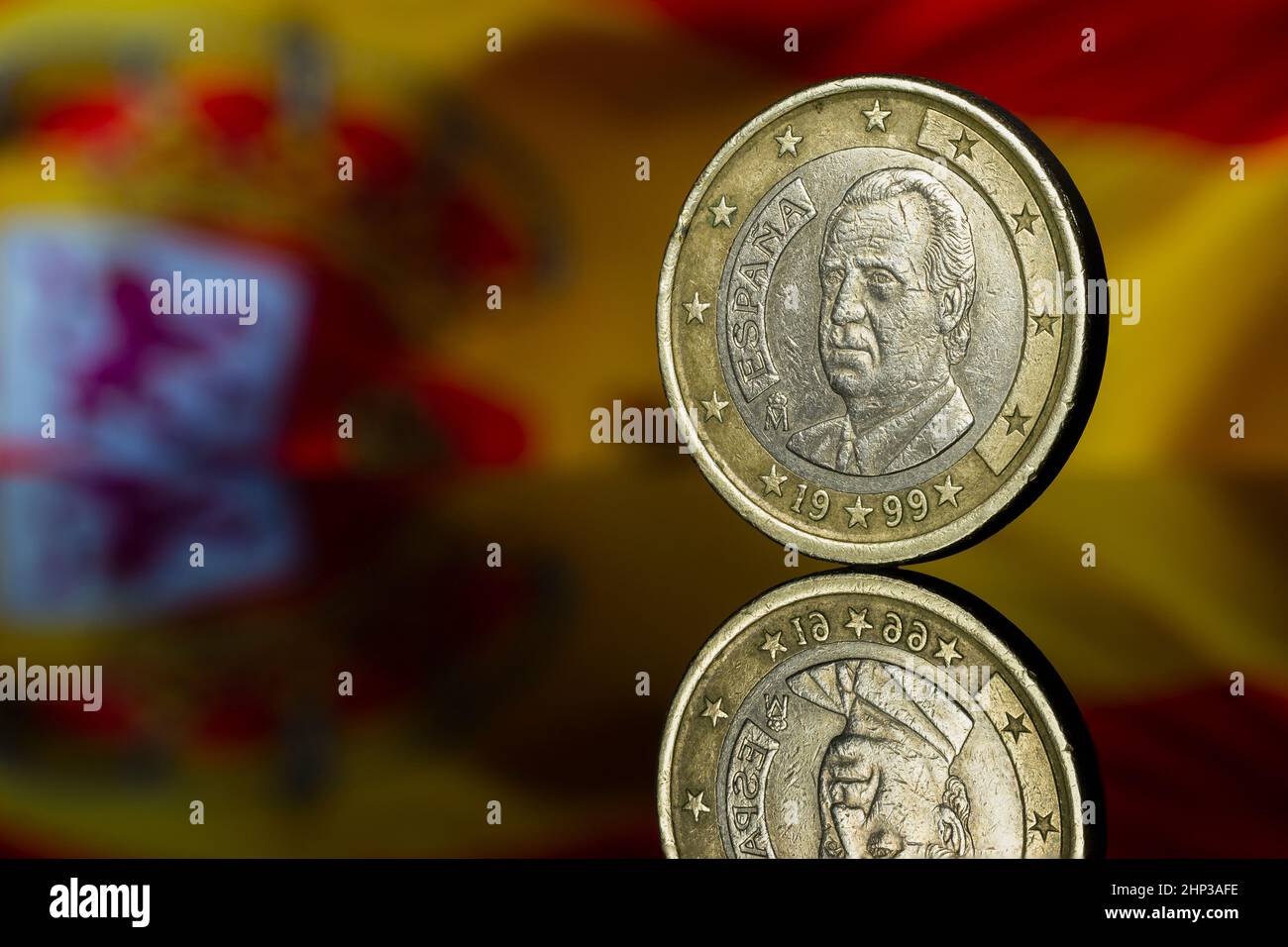 Juan Carlos I Roi d'Espagne Euro coin avec l'Espagne drapeau flou dans l'arrière-plan reflété Banque D'Images