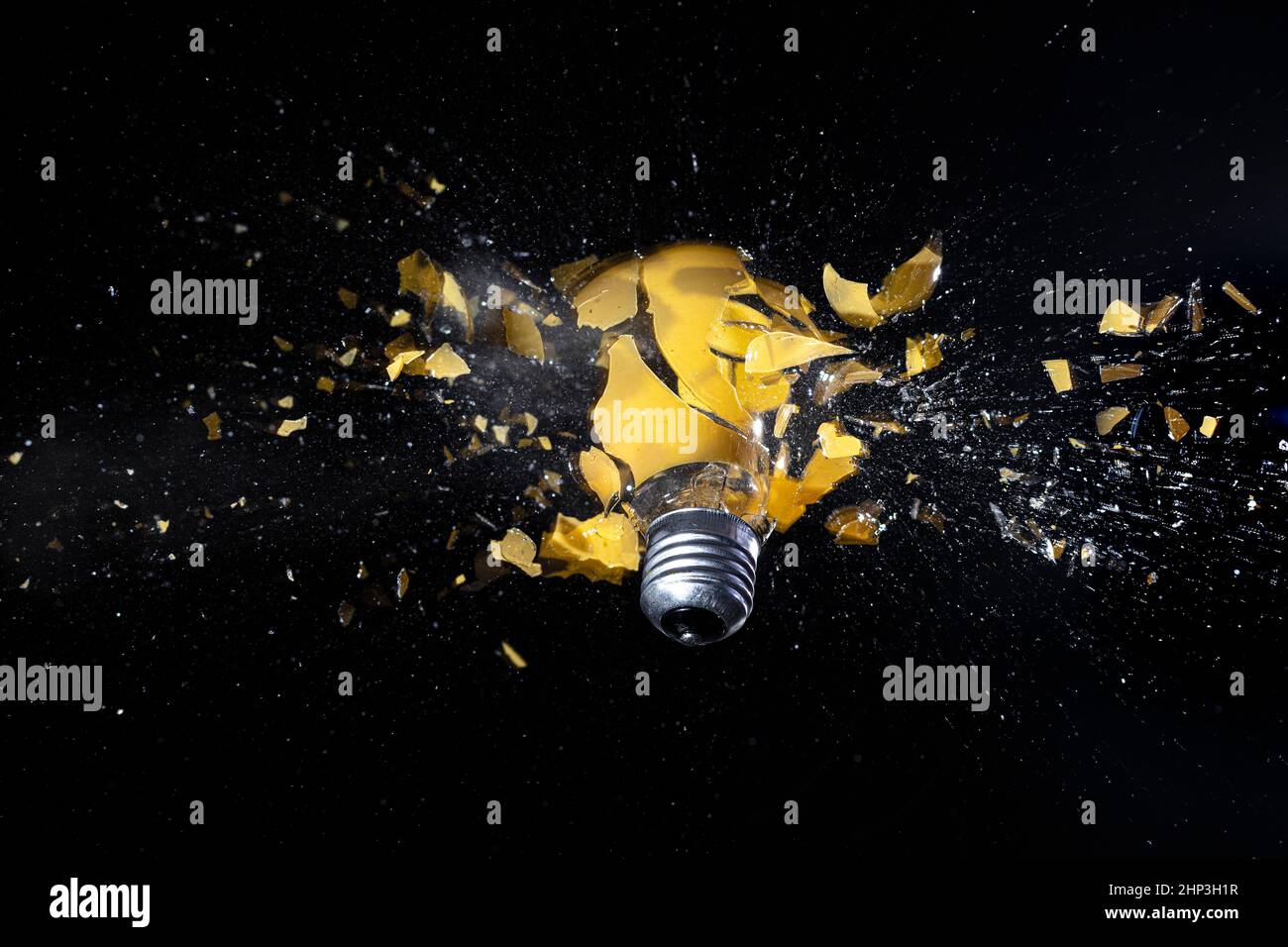 photo à grande vitesse d'une ampoule jaune qui explose sur le noir. Banque D'Images