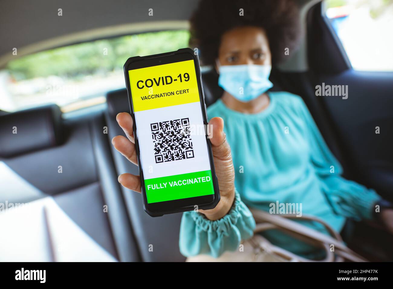 Femme d'affaires afro-américaine de taille moyenne montrant un téléphone avec code qr vacciné Covid-19 en voiture Banque D'Images