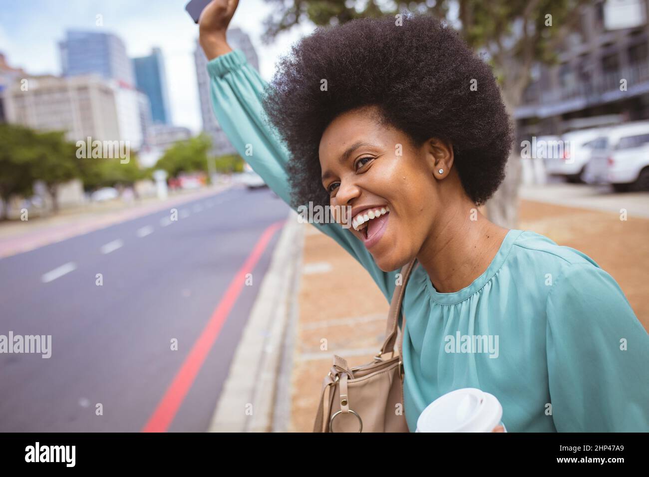 Bonne femme d'affaires afro-américaine de taille moyenne avec bras levé debout sur le sentier de la ville Banque D'Images