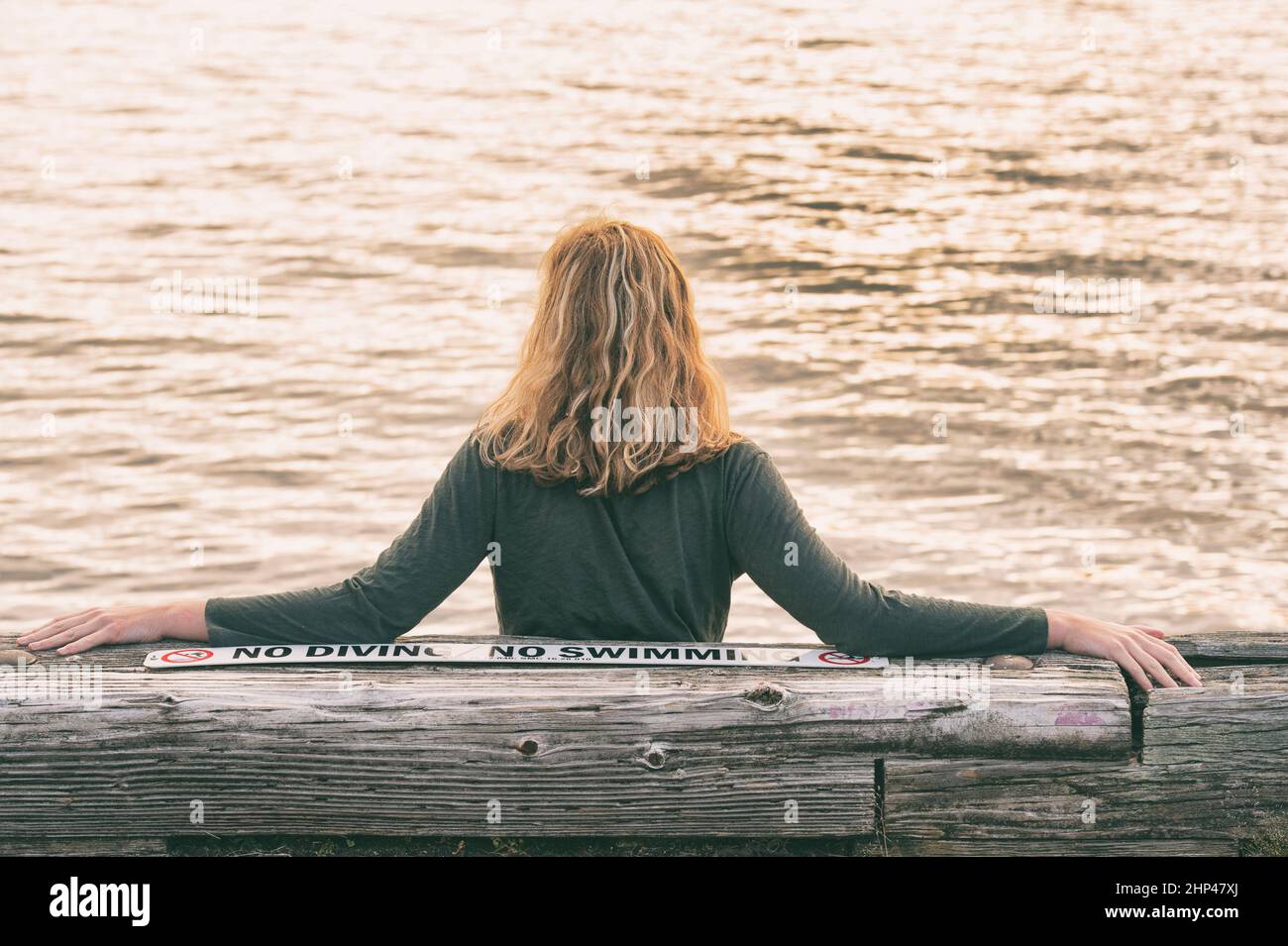 Jeune femme assise contemplant l'eau du lac. Les jeunes espèrent, rêves et ponders par le lac Washington à Seattle, WA Banque D'Images