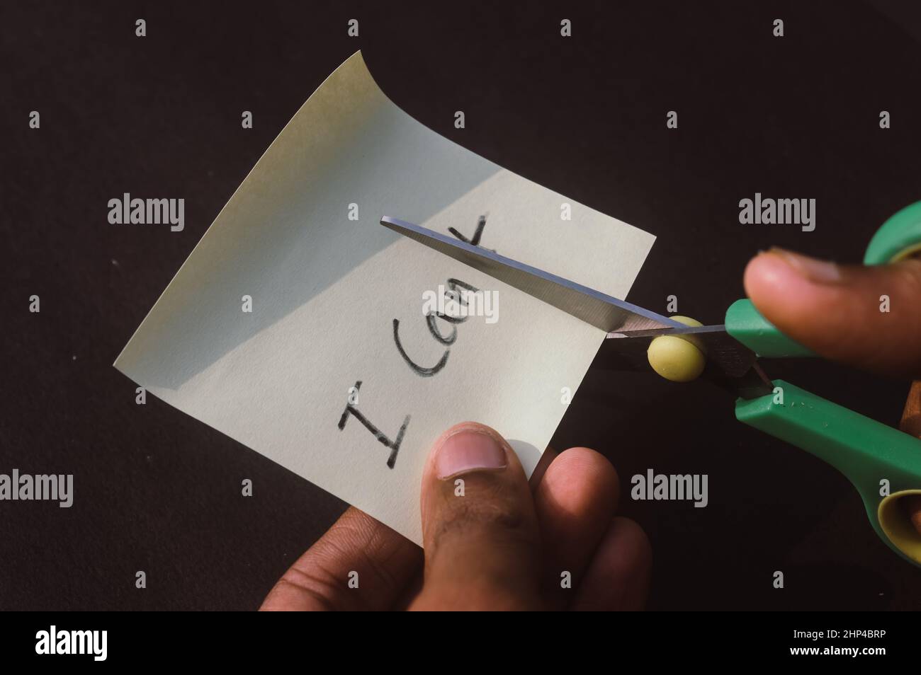 Les mains coupant la lettre T de ne peut pas avec des ciseaux écrit du texte sur le papier de rappel rectangle.Détermination succès défi croire motivation aspiration Banque D'Images