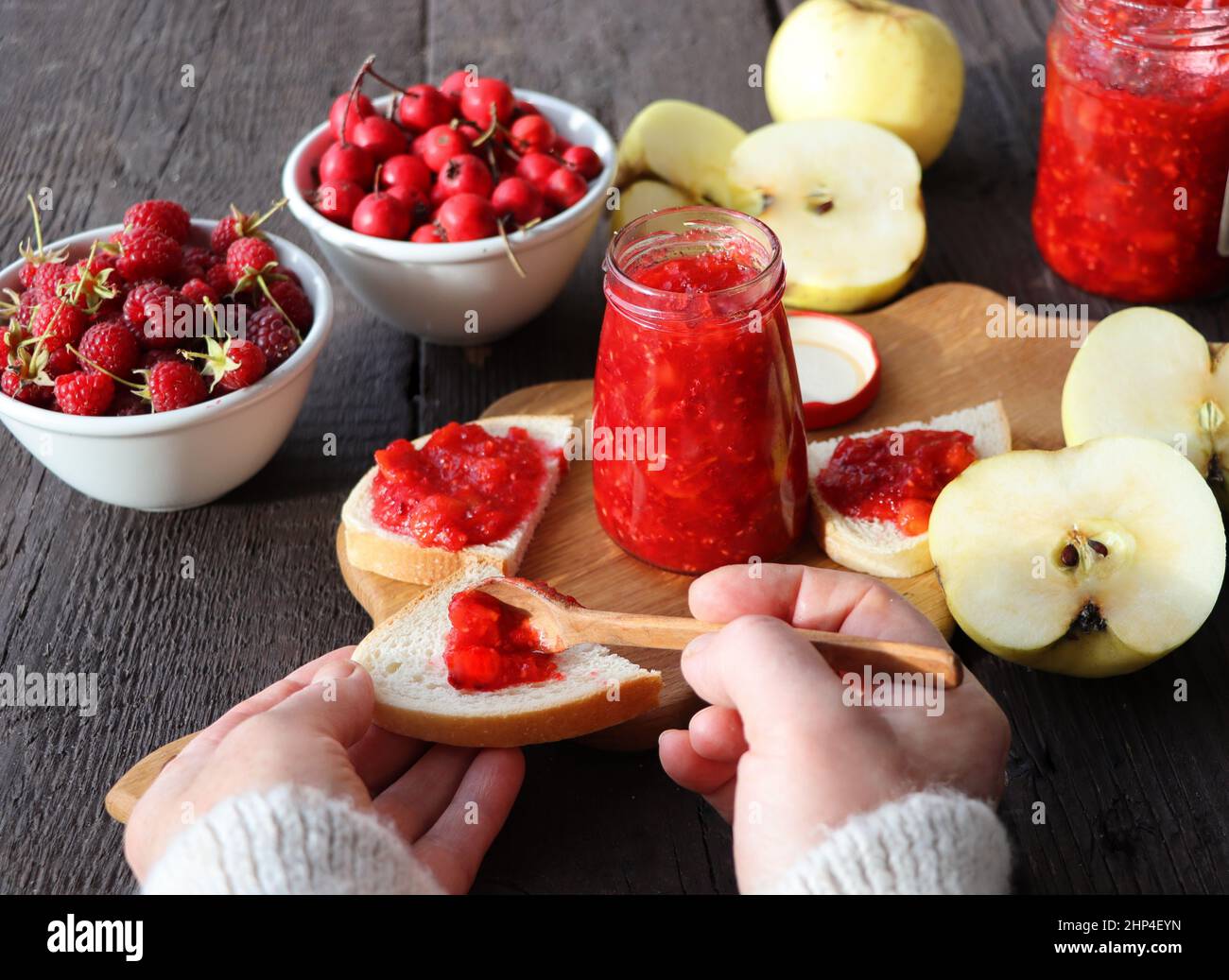 Pot en verre avec différentes sortes de fruits et de baies sur une table en bois.Pomme, framboise, confiture d'aubépine . Banque D'Images