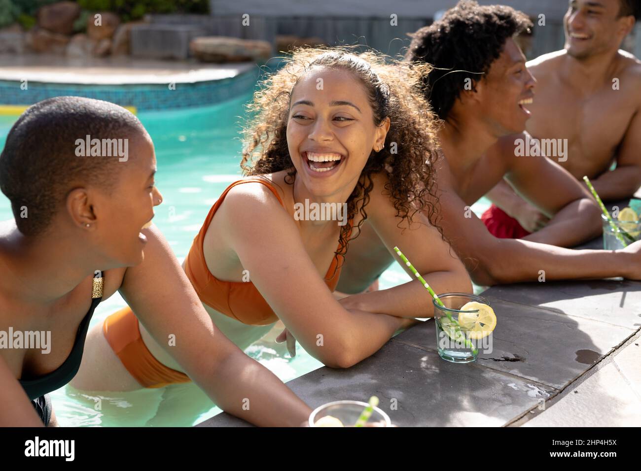 De jeunes amis multiraciaux joyeux se penchent sur la piscine par beau temps Banque D'Images