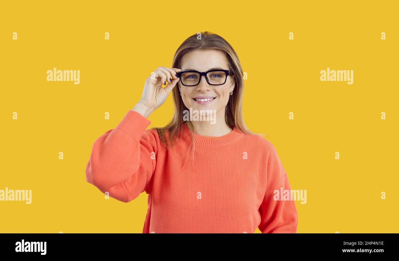 Portrait d'une jeune femme avec un beau sourire portant des lunettes isolées sur fond jaune. Banque D'Images