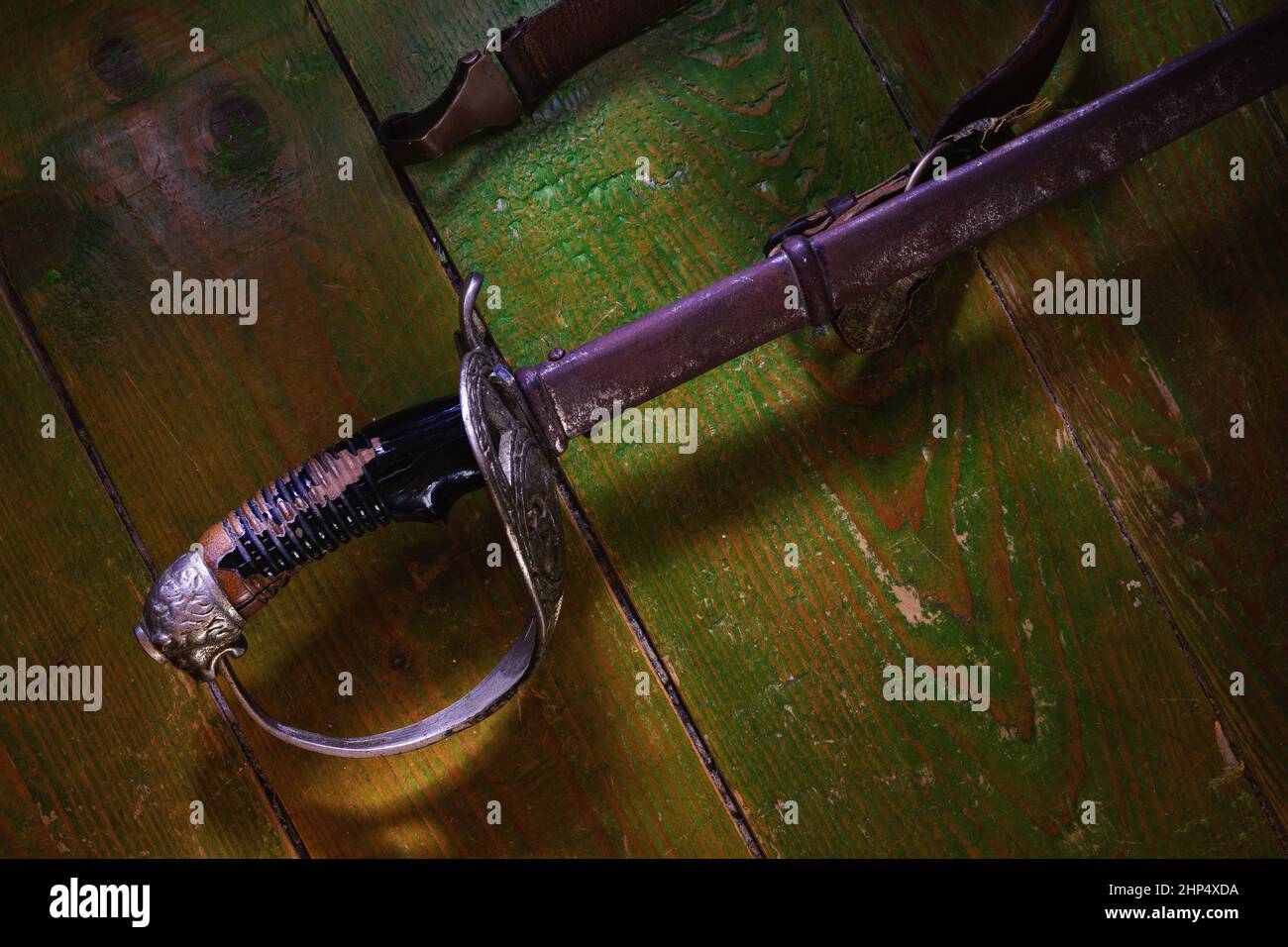 Ancienne épée rouillée sur un sol en bois vert. Banque D'Images