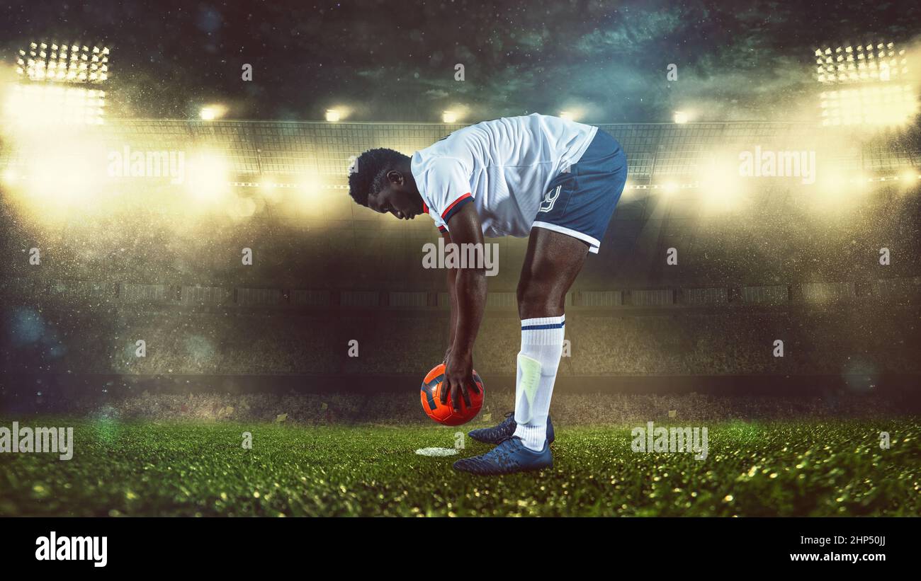 Scène de football de nuit avec le joueur en blanc et uniforme plaçant le ballon pour le coup Banque D'Images