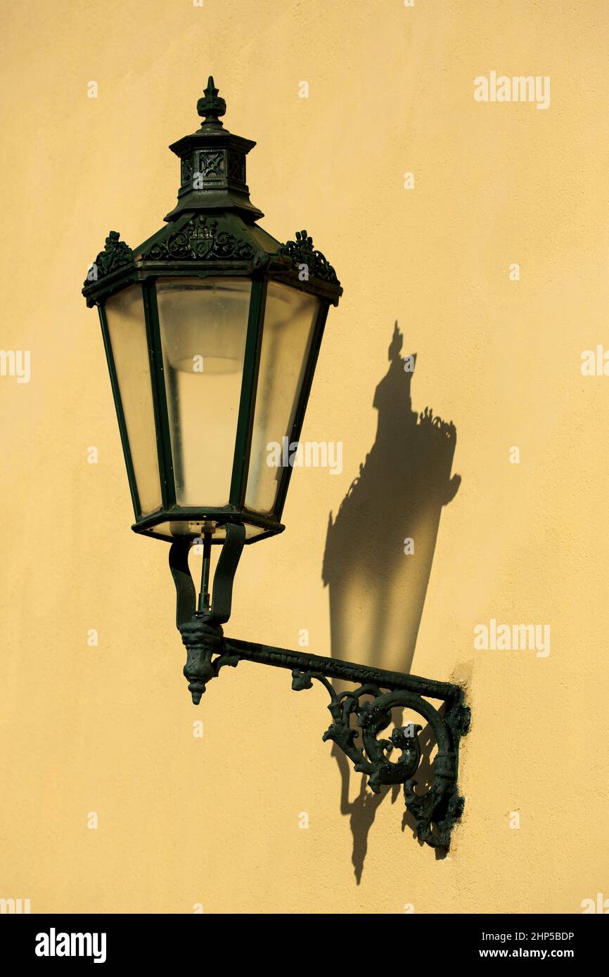 Un passage pavé avec le mur de contrefort jaune du château de Prague et un lampadaire traditionnel orné, par une journée ensoleillée avec des ombres, Prague, Tchèque Banque D'Images