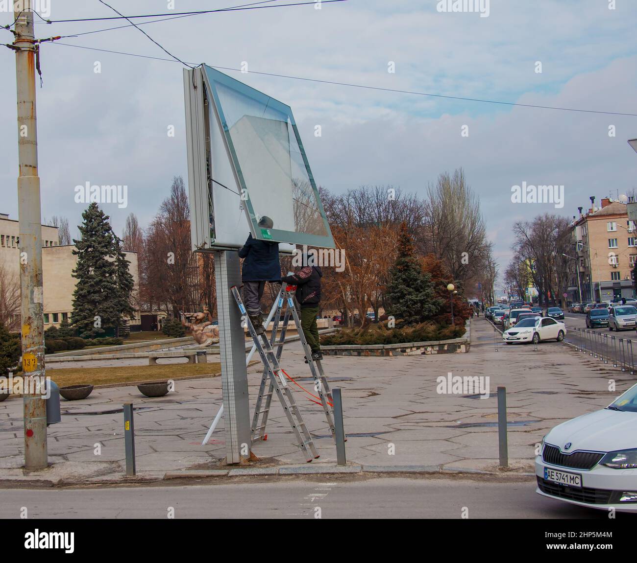 Dnepropetrovsk, Ukraine - 02.09.2022: Installation de publicité extérieure dans la ville. Des spécialistes grimpent les escaliers jusqu'au panneau d'affichage. Travail risqué. Travail Banque D'Images