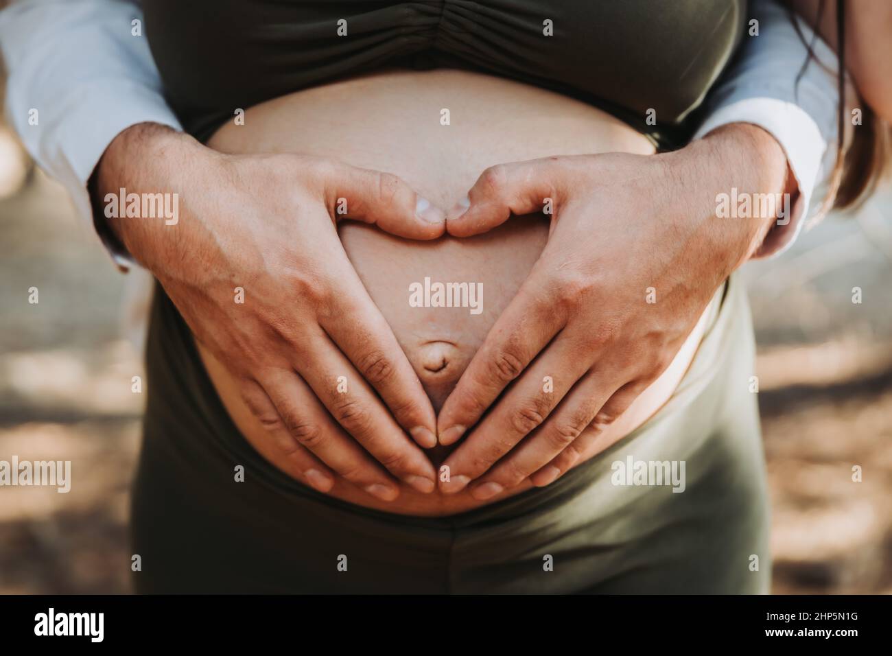 Le cœur du père forme les mains touchant le ventre de maternité de la mère enceinte. Concept de grossesse. Parenté Banque D'Images