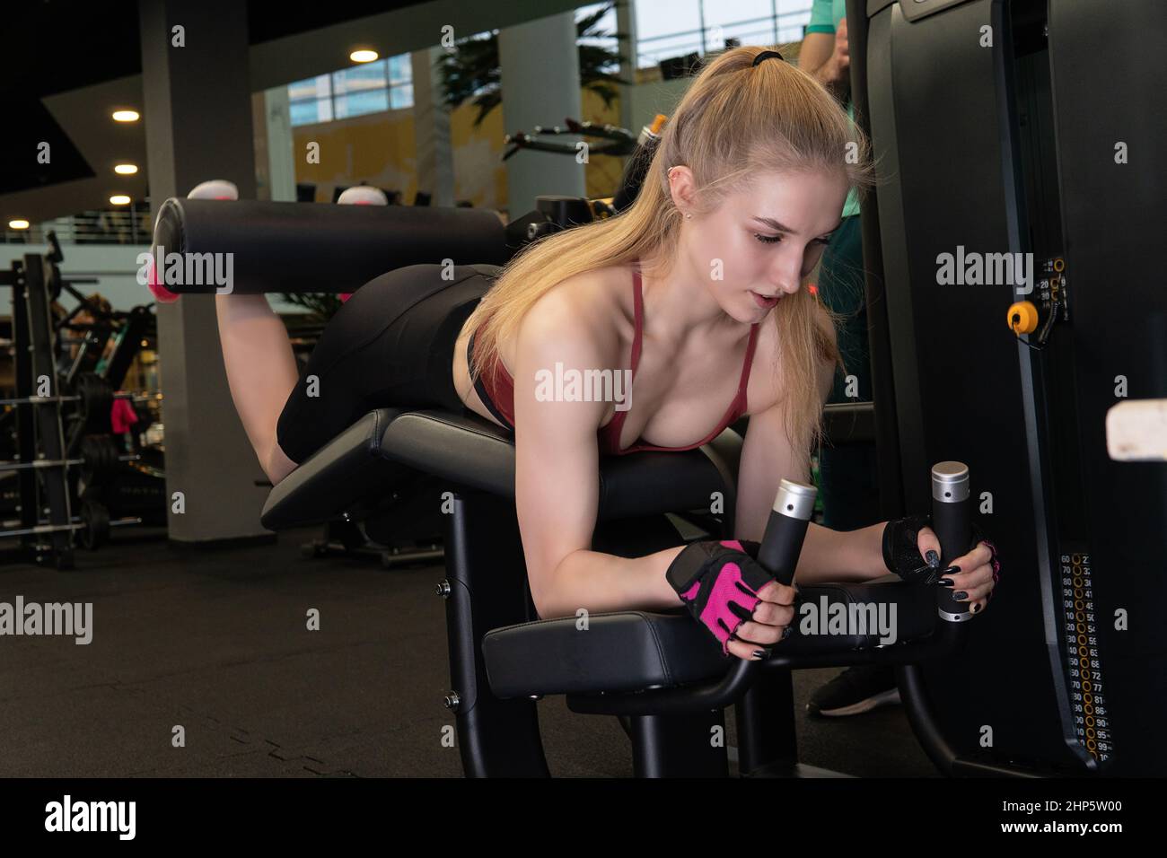 L'entraînement dirigé par un instructeur aide un beau client à effectuer des exercices dans un club de remise en forme, le concept de jouer du sport avec un loisir professionnel de gym Banque D'Images