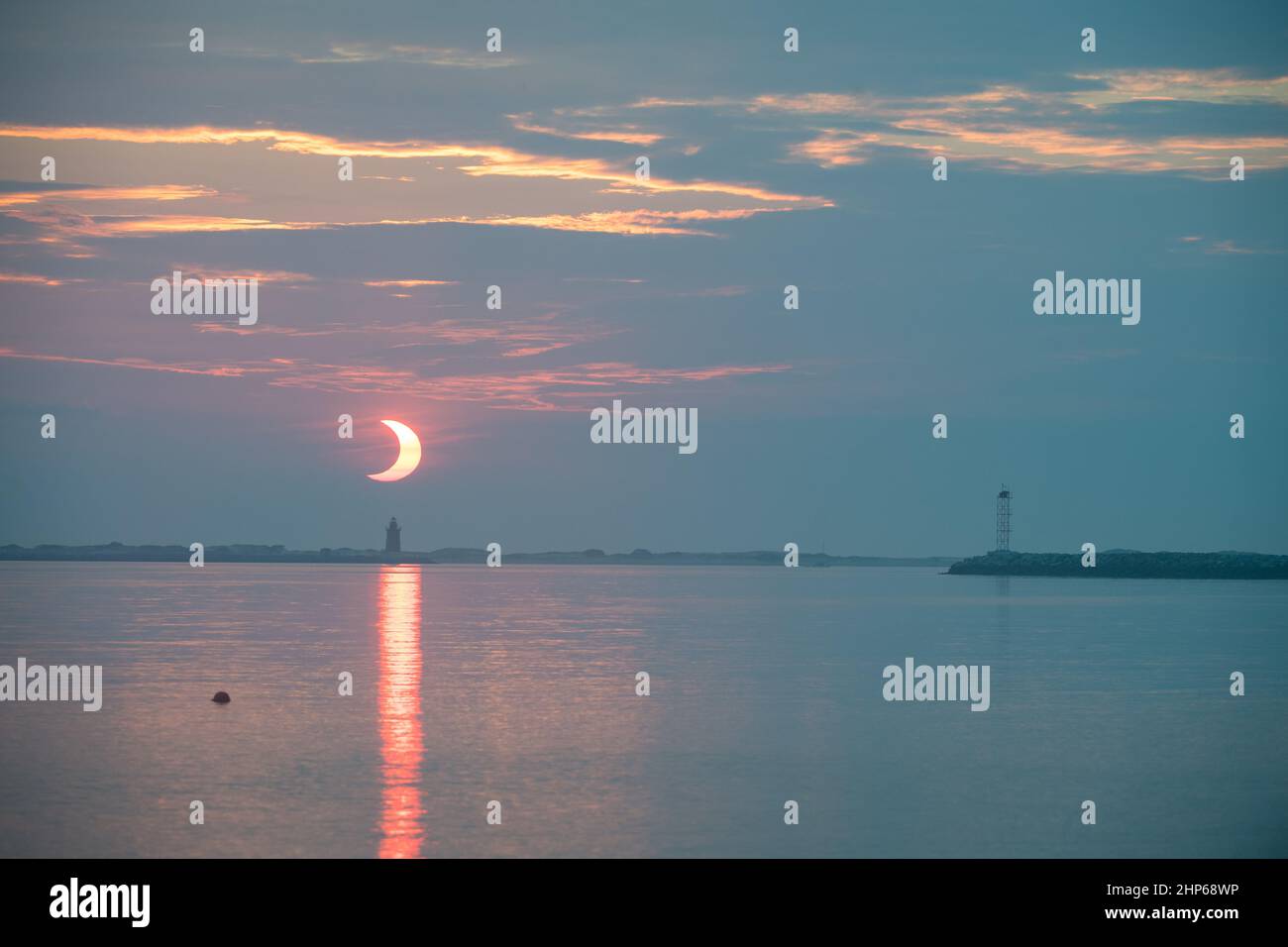Une éclipse solaire partielle est vue lorsque le soleil se lève derrière le phare de Delaware Breakwater, le jeudi 10 juin 2021, à Lewes Beach, dans le Delaware. L'éclipse solaire annulaire ou « anneau de feu » n'est visible que dans certaines parties du Groenland, du nord de la Russie et du Canada. Banque D'Images