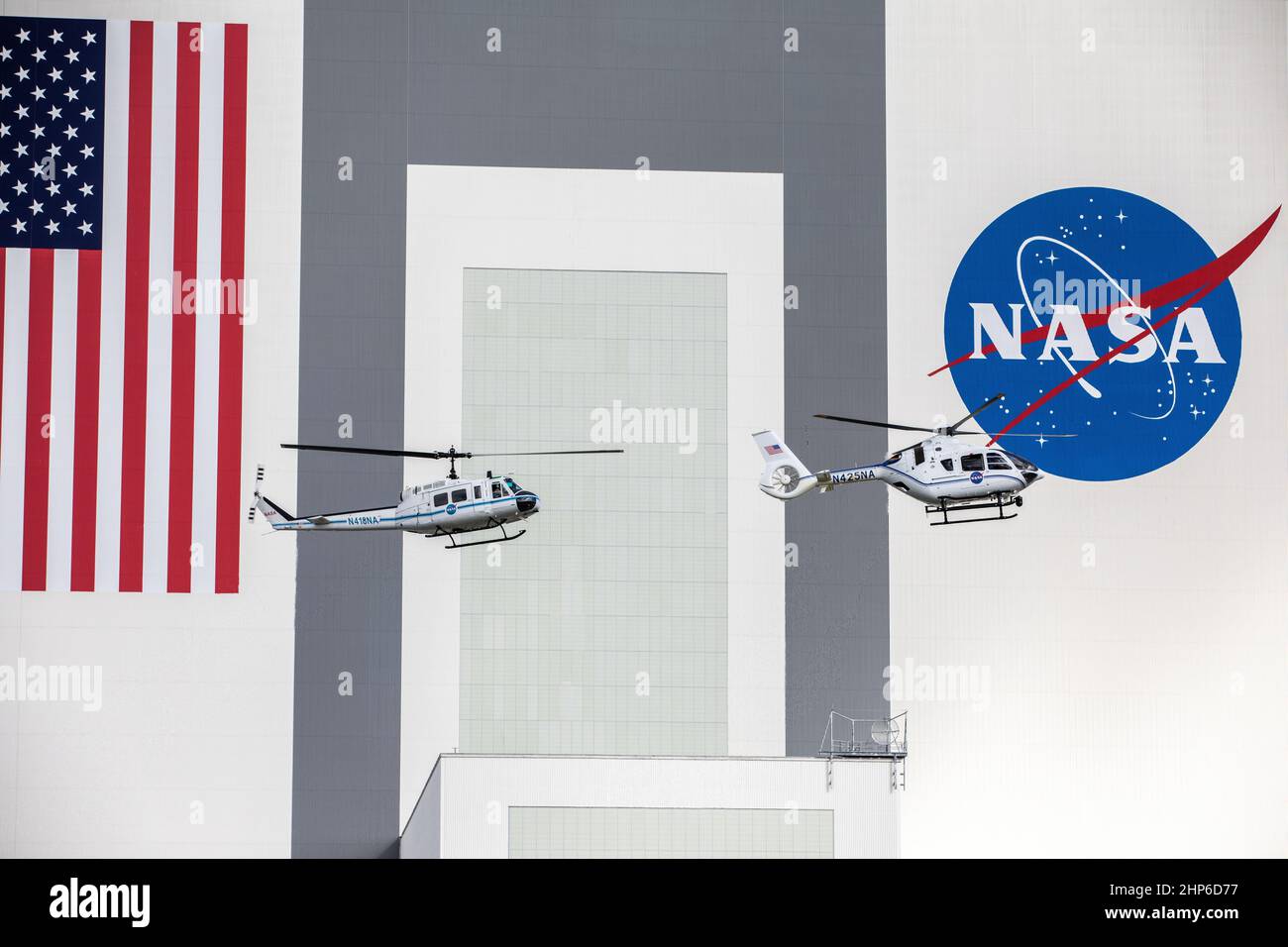 Le 27 octobre 2020, devant l'emblématique bâtiment d'assemblage de véhicules du Kennedy Space Center de la NASA, les hélicoptères Bell Huey 2 (à gauche) et Airbus H135 utilisés pour les opérations de sécurité dans le port spatial de Floride effectuent un vol ensemble avant que les Hueys ne soient retirés de leur service Banque D'Images