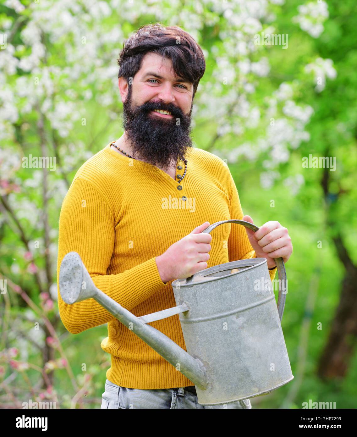 Travaux de jardinier. Agriculteur travaillant dans le jardin. Homme barbu avec arrosoir peut se préparer à la plantation. Ressort. Banque D'Images