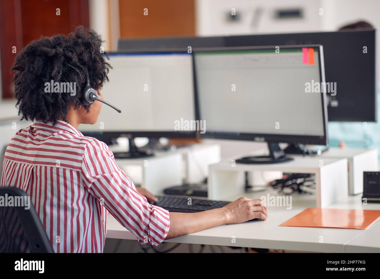 Une jeune femme se concentre sur un travail à l'ordinateur dans une atmosphère agréable au bureau. Employés, travail, bureau Banque D'Images