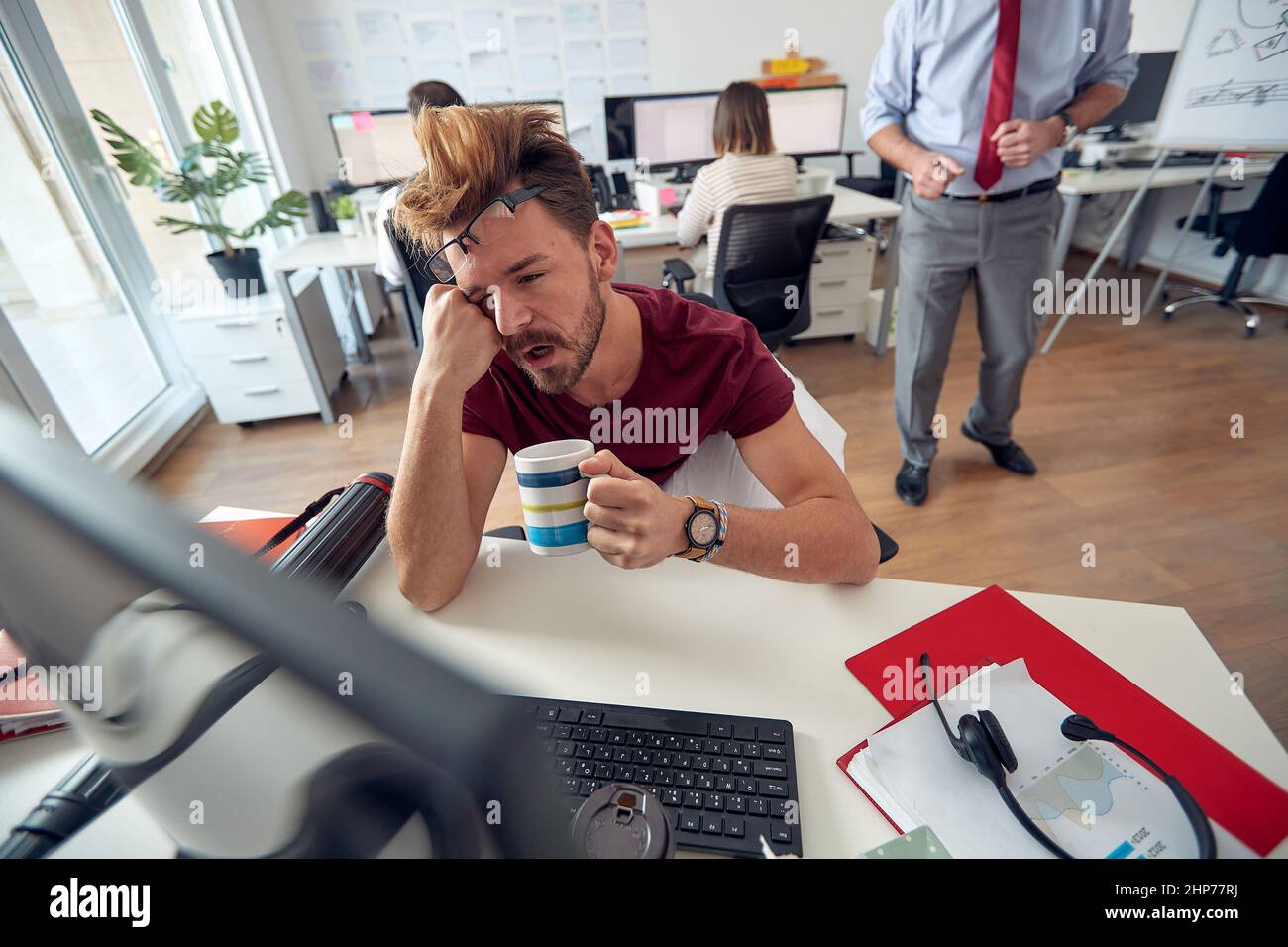 Un employé de sexe masculin fatigué s'est endormi tout en travaillant dans une atmosphère uniforme au bureau. Employés, travail, bureau Banque D'Images