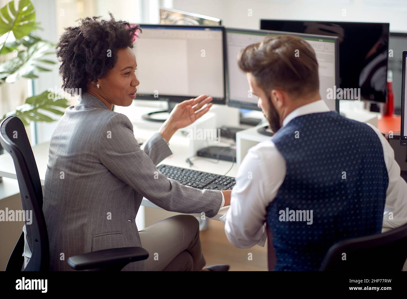 Une jeune employée parle avec son collègue au bureau dans une atmosphère de travail au bureau. Employés, travail, bureau Banque D'Images