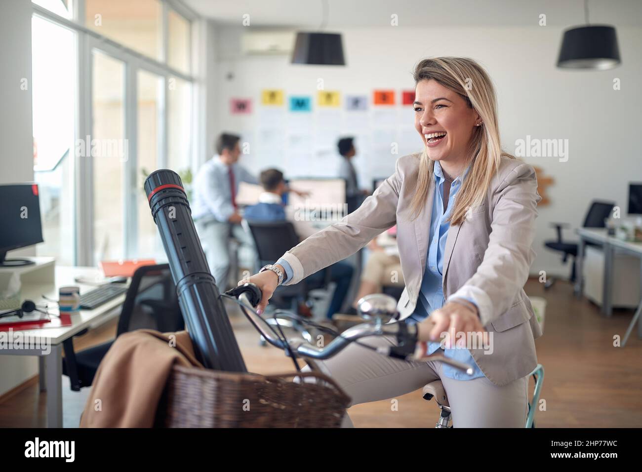 Une jeune employée pose pour une photo tout en faisant du vélo dans une atmosphère détendue lors d'une pause au bureau. Employés, travail, bureau Banque D'Images