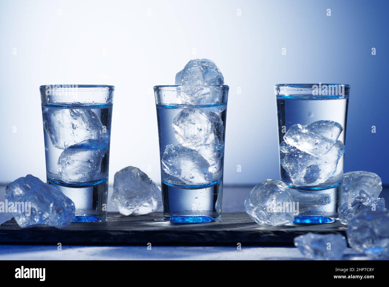 Verre de vodka avec glace sur fond bleu, mise au point sélective Banque D'Images