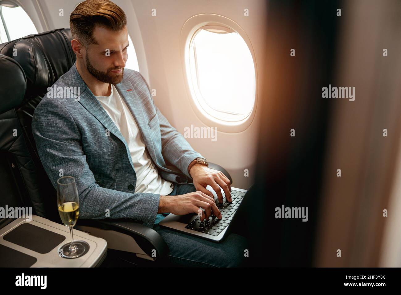 Homme barbu travaillant sur un ordinateur portable dans un avion Banque D'Images