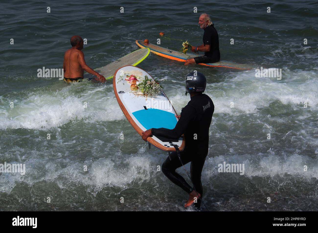 Un surfeur porte une offrande de fleurs sur son plateau quand, En guise de protestation contre la marée noire de Repsol qui a provoqué une catastrophe écologique sur les côtes de Lima et El Callao, un groupe de militants a organisé une cérémonie de mariage avec la mer sur la plage de Makaha à Lima. Le 15th janvier, plus de 10 000 000 barils de pétrole ont été déversés dans la mer à la raffinerie de la Pampilla exploitée par Repsol, une compagnie pétrolière espagnole, qui a produit l'une des plus grandes catastrophes écologiques du Pérou. Banque D'Images