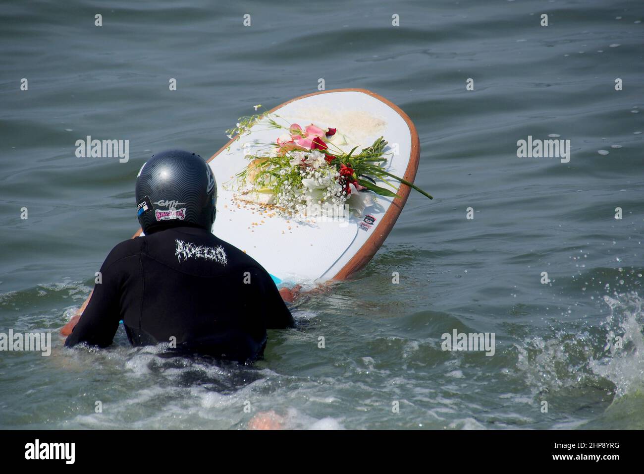 Un surfeur porte une offrande de fleurs sur son plateau quand, En guise de protestation contre la marée noire de Repsol qui a provoqué une catastrophe écologique sur les côtes de Lima et El Callao, un groupe de militants a organisé une cérémonie de mariage avec la mer sur la plage de Makaha à Lima. Le 15th janvier, plus de 10 000 000 barils de pétrole ont été déversés dans la mer à la raffinerie de la Pampilla exploitée par Repsol, une compagnie pétrolière espagnole, qui a produit l'une des plus grandes catastrophes écologiques du Pérou. Banque D'Images