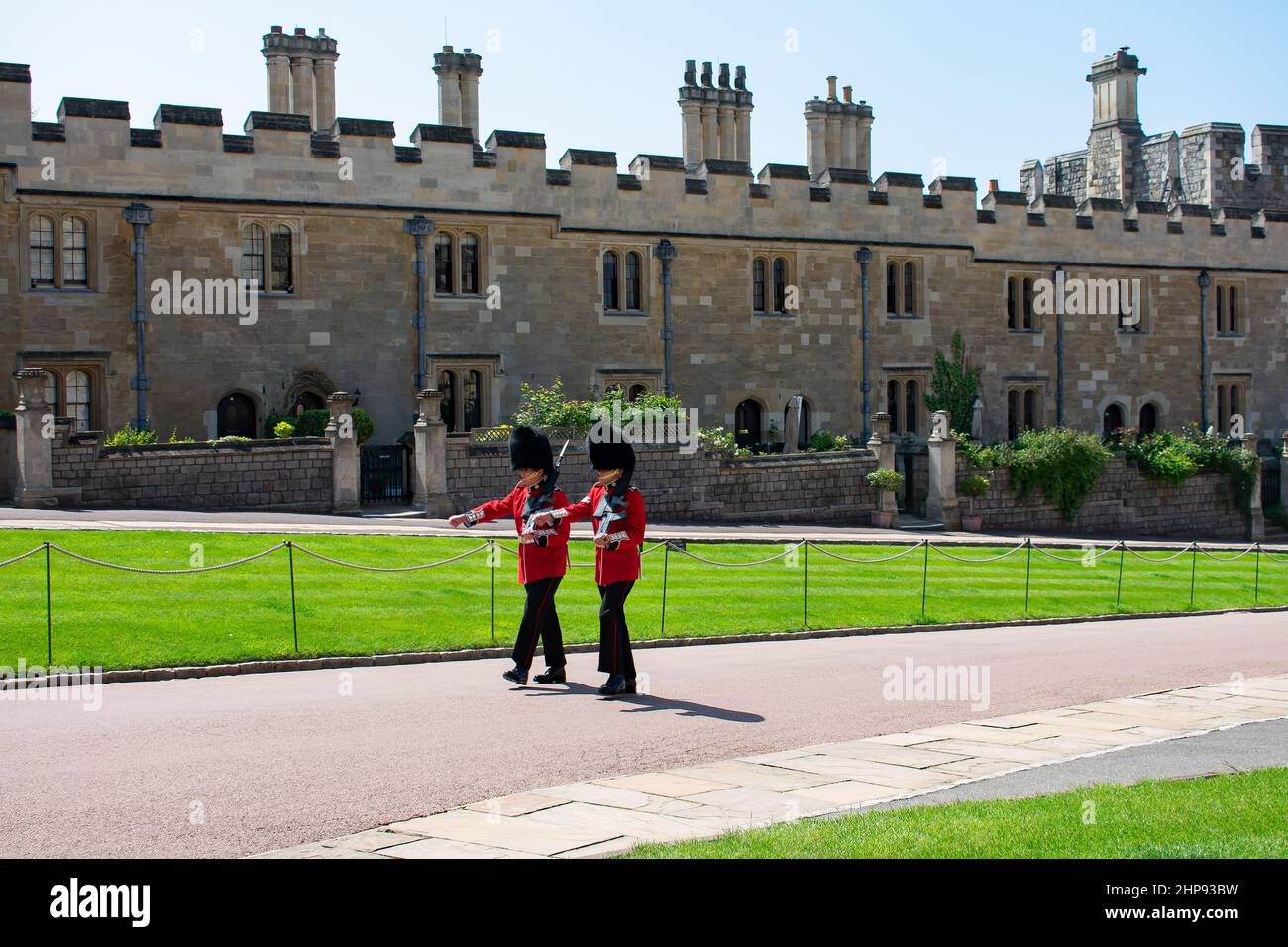 Deux gardes du château de Windsor portant des uniformes rouges et des barbes défilent sur le chemin, passant devant les résidences des Chevaliers militaires du gouverneur. Windsor, Royaume-Uni. Banque D'Images