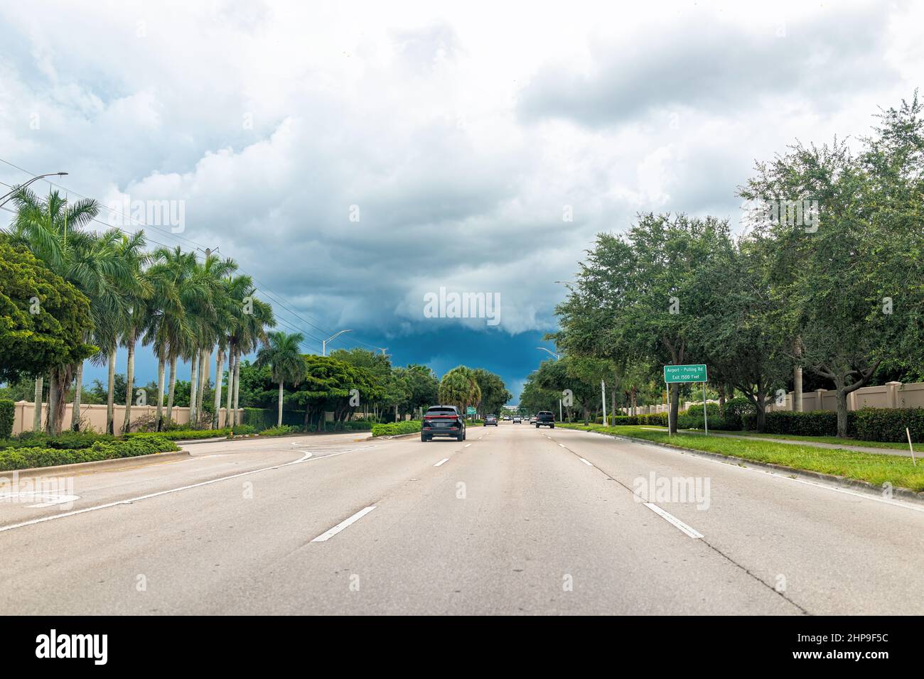 Naples, États-Unis, l'aéroport de tirer une rue vide ouverte avec des voitures dans la circulation le jour nuageux orageux avec panneau de point de vue de la conduite Banque D'Images