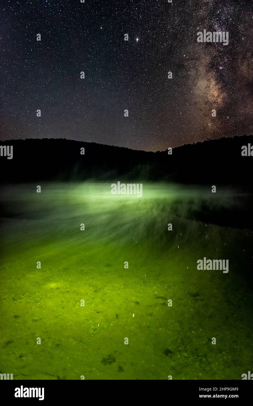 Ciel nocturne avec une voie laiteuse sombre dans Spruce Knob Lake, Virginie occidentale avec brume verte montante au-dessus de l'eau et reflet de la vue verticale des étoiles Banque D'Images