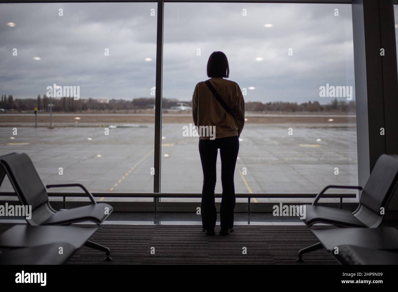 Une fille se tient devant une grande fenêtre en vitraux à l'intérieur de l'aéroport Banque D'Images