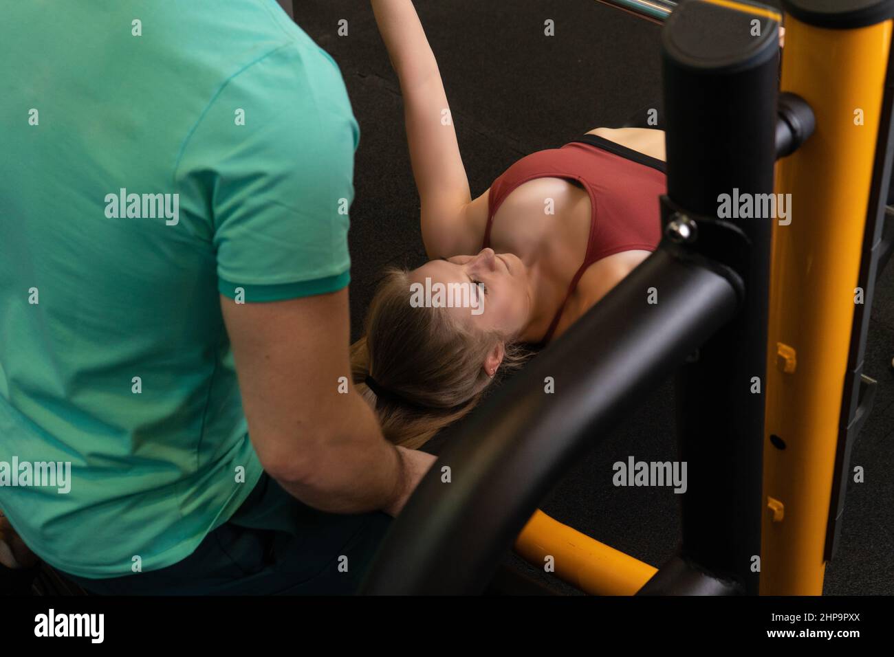 L'entraînement dirigé par un instructeur aide un beau client à effectuer des exercices dans un club de remise en forme, le concept de jouer du sport avec un loisir professionnel de gym Banque D'Images