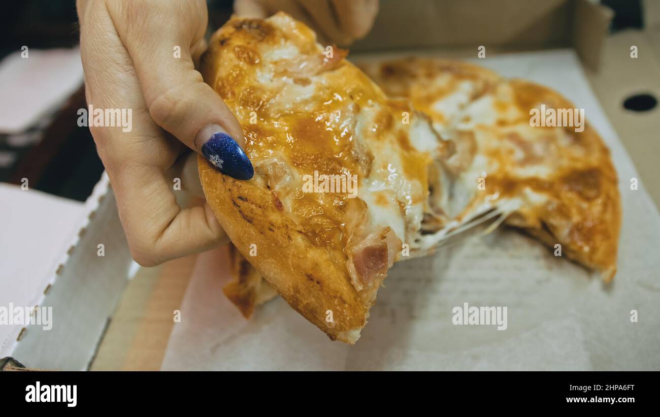 Une fille mange du fromage pizza quatre. Gros plan de la jeune femme bouche gailis manger de la pizza et mâcher dans le restaurant en plein air. Mains humaines prenant des morceaux de Banque D'Images