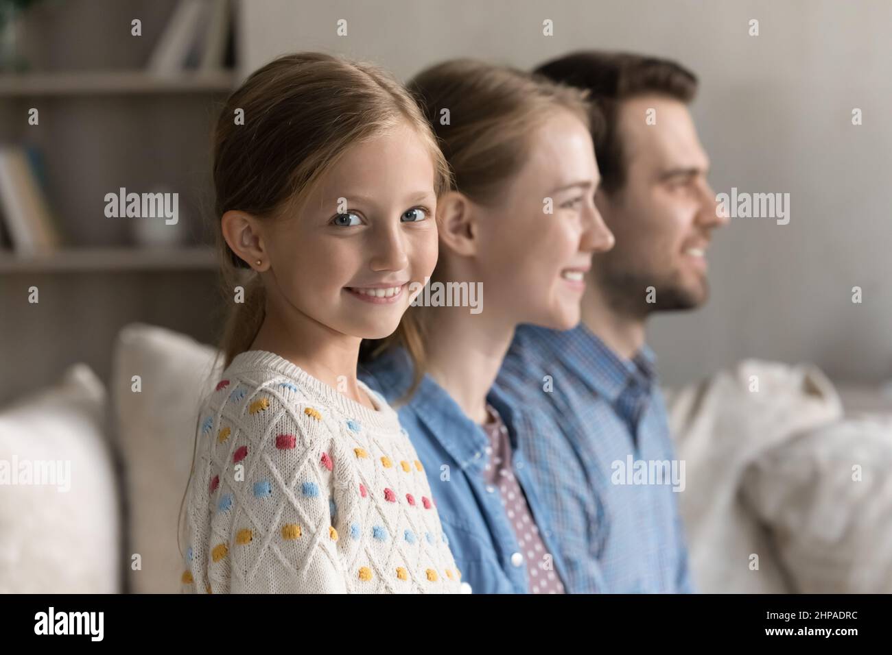 Bonne petite fille adorable assise sur un canapé à la maison Banque D'Images