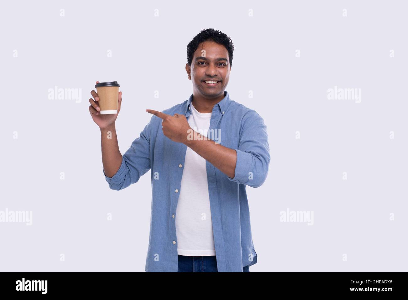 Un homme indien qui tient une tasse de café à emporter le montre. Un Indien avec un café à emporter en main. Isolé Banque D'Images