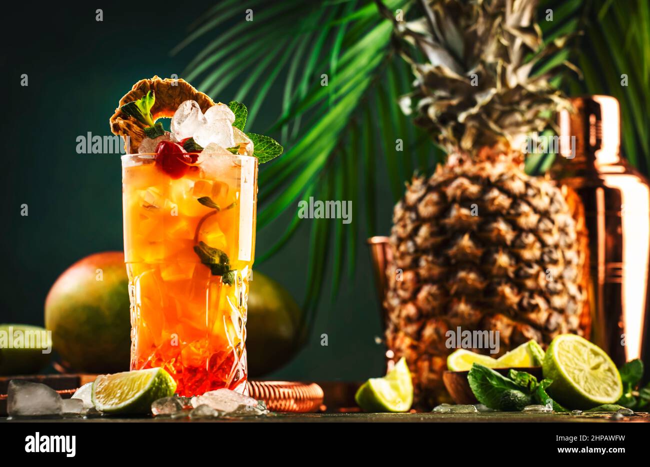Cocktail alcoolisé avec vodka, jus d'ananas, mangue, sirop rouge et glace.  Boisson longue ou cocktail froid d'été. Arrière-plan tropical foncé avec  feuilles de palmier Photo Stock - Alamy
