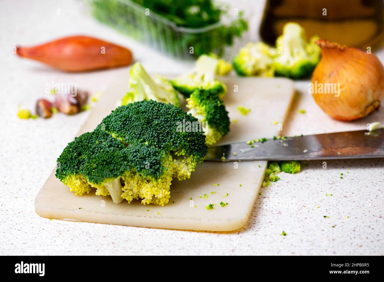 Fleurons de brocoli, oignons, ail, persil, bouteille d'huile d'olive et couteau sur le plan de cuisine sur la table. Banque D'Images