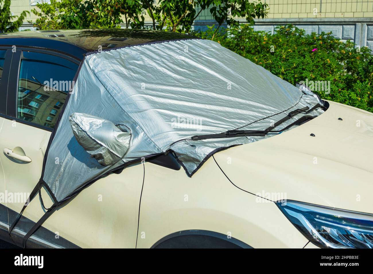 Une voiture dans un parking avec un pare-brise recouvert d'un réflecteur  pare-soleil à l'extérieur, pour protéger la partie en plastique de  l'intérieur de la voiture et le gl Photo Stock - Alamy
