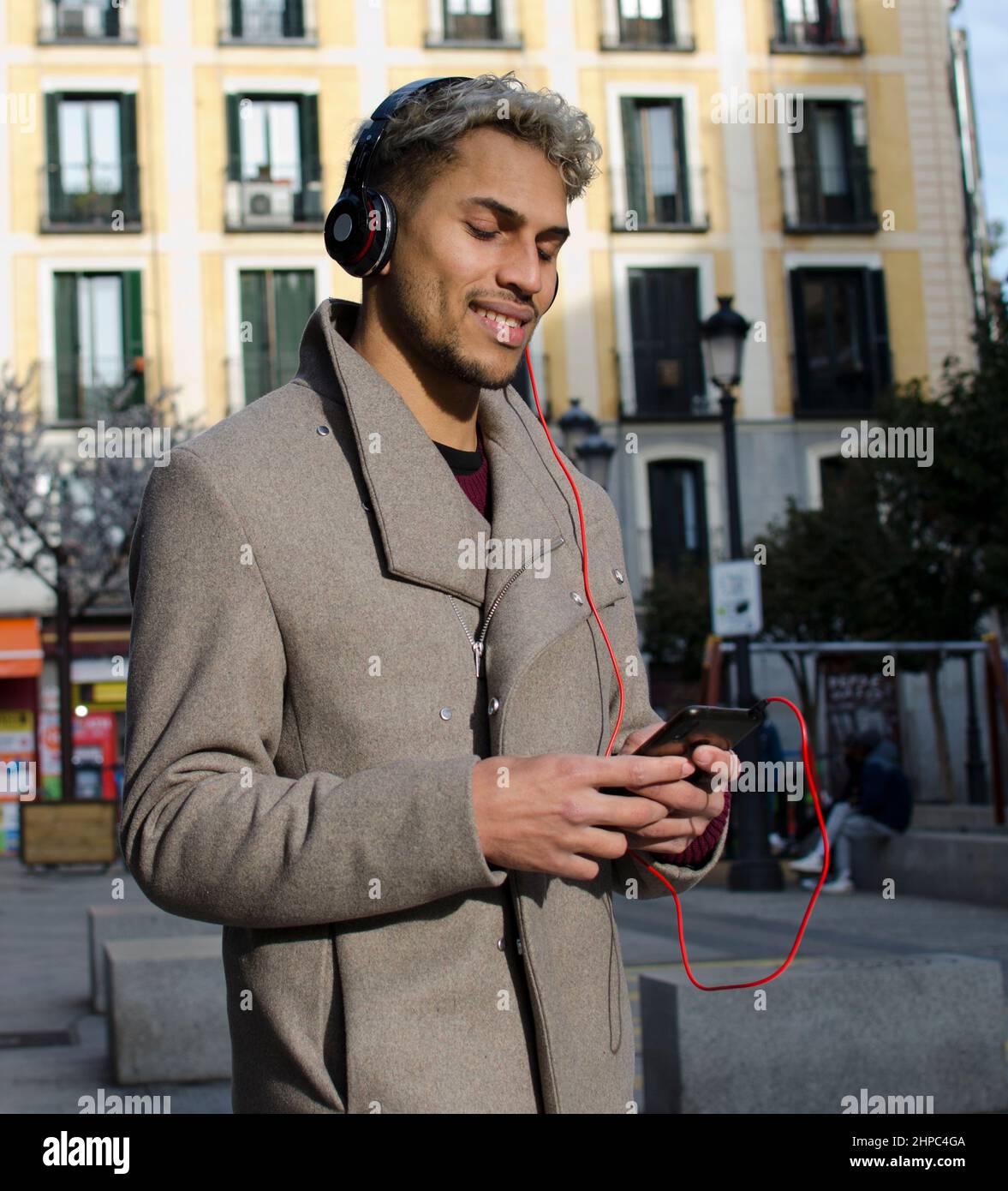 Jeune homme avec casque tenant le smartphone à la main et écoutant de la musique dans la ville Banque D'Images