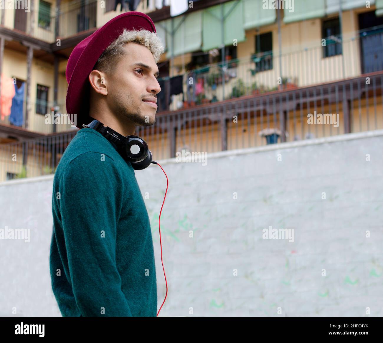 Jeune homme avec casque et chapeau rouge à la main dans la ville Banque D'Images