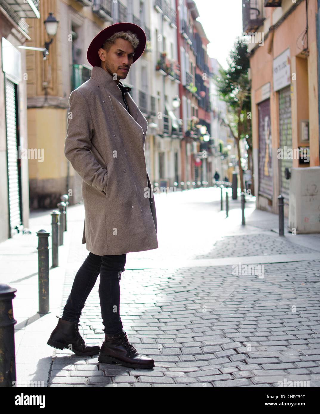 Jeune mannequin tendance avec veste grise et chapeau rouge dans la rue Banque D'Images