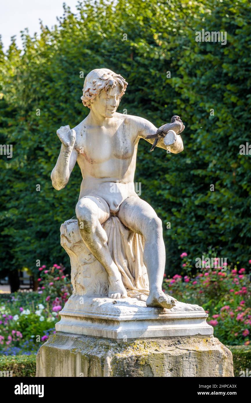 Un pigeon est assis sur le bras de la statue du Snake Charmer dans le jardin du Palais-Royal à Paris, France. Banque D'Images