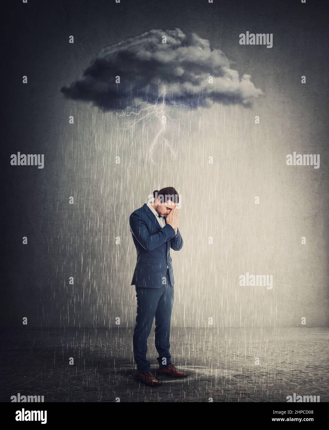 Pessimiste et déprimé homme d'affaires debout sous la pluie alors que les pensées négatives se dresse au-dessus de sa tête comme un nuage de tempête. Personne souffrant d'anxiété a Banque D'Images