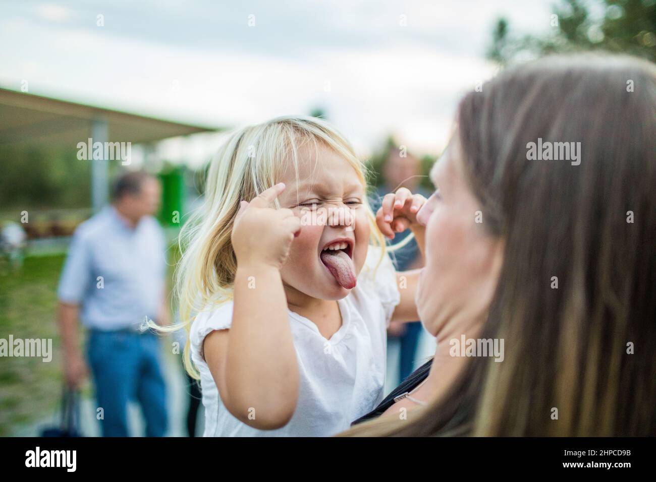 Une jeune fille tout-petits fait un visage fou et ridicule à sa mère. Banque D'Images