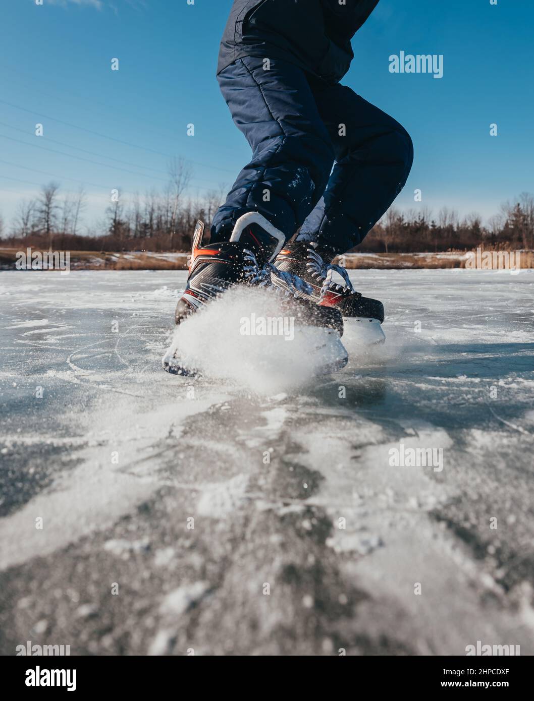 Courte vue rapprochée des patins de hockey s'arrêtant sur la glace en plein air. Banque D'Images