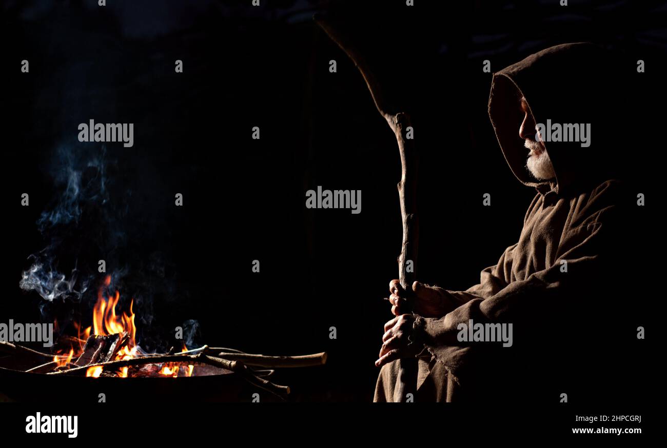 Vieil homme pauvre assis près du feu avec une flûte au Moyen-âge Banque D'Images