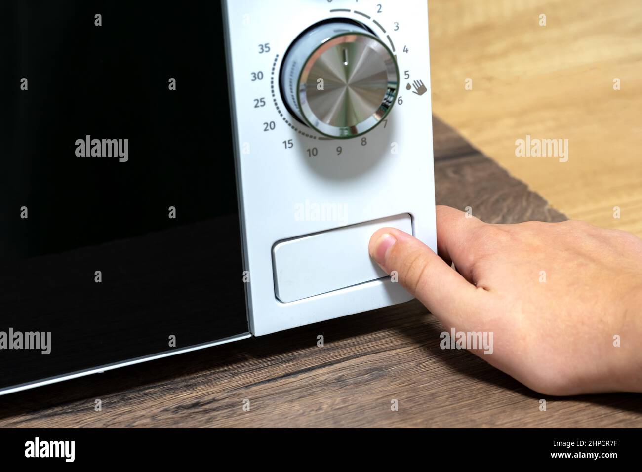 La main appuie sur le bouton. Ouverture du four à micro-ondes. Utilisation d'un four à micro-ondes. Banque D'Images